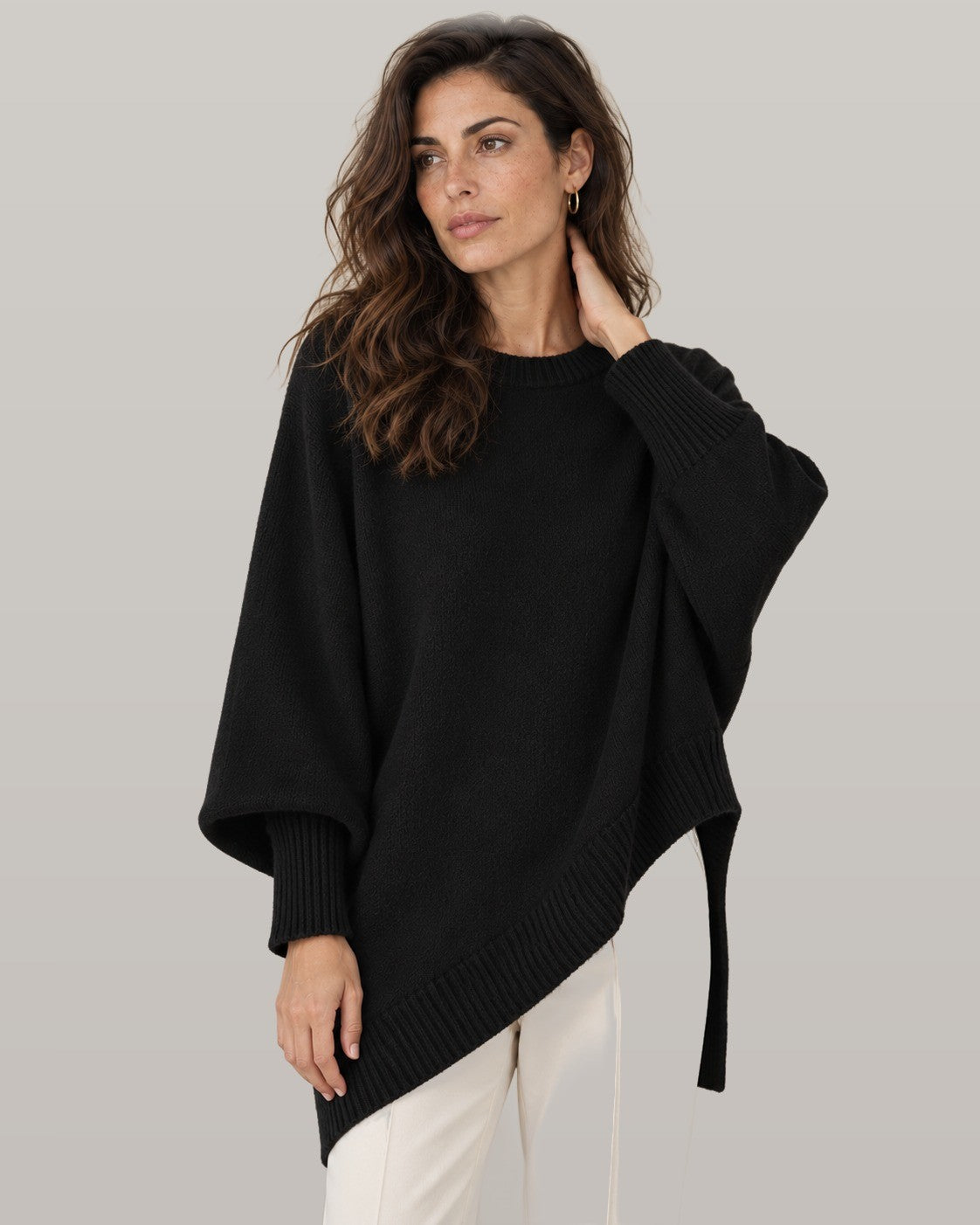 Draped asymmetric knit poncho in black, front view